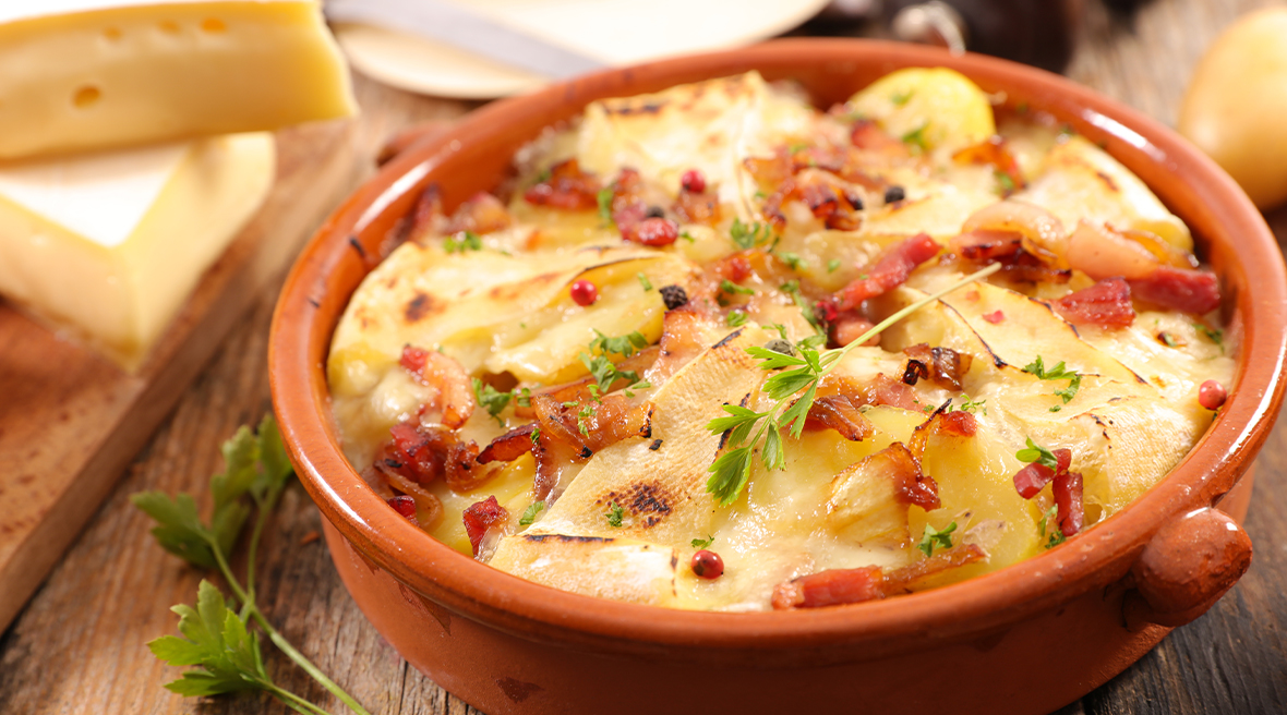 Red dish filled with potatoes, cheese and onion with a green garnish